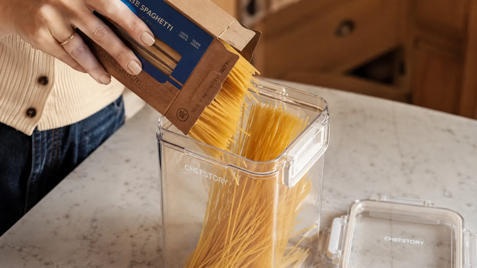 CHEFSTORY container being filled with dry pasta from an open box on a kitchen counter to show the container mouth width